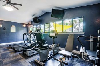 A gym with a variety of equipment including treadmills, exercise bikes, and a television.